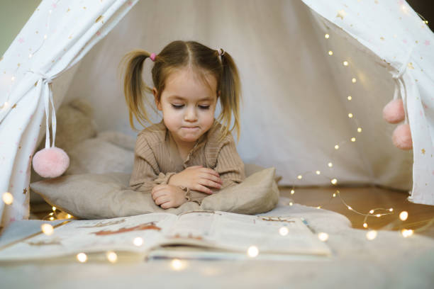 istock Child whit book lying in tent 2198920338