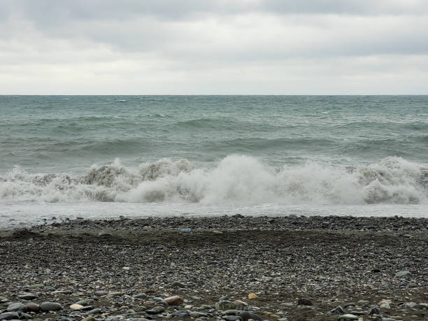 Powerful waves crashing onto a pebble beach in Batumi under a cloudy horizon, showcasing natural energy and the beauty of coastal landscapes.