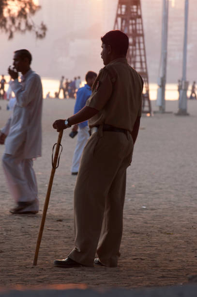 A guard stands with a stick on an Indian beach at sunset