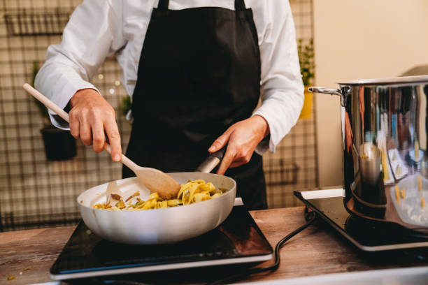 istock Chef preparing pasta in a pan with artichokes and zucchini 2198923982