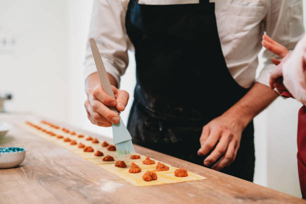 istock Chef spreading filling on fresh pasta sheets, making ravioli 2198924018