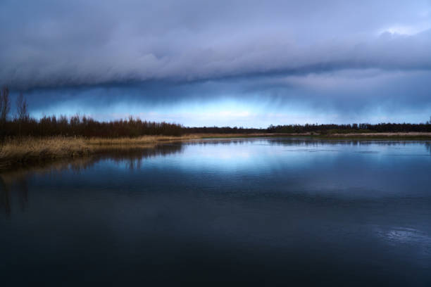 Behand the storm we see a beatifull blue sky. Reflection in the water of the clouds and the falling rain in the distance.