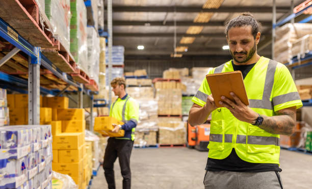 istock Men working in distribution warehouse in Sydney, Australia, examining merchandise and managing inventory with expertise 2198928381