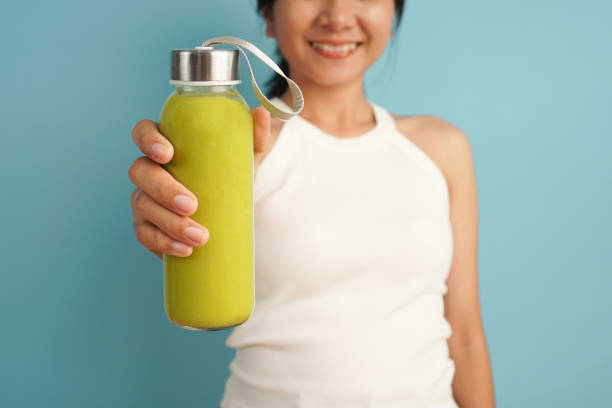 close up woman holding smoothies avocado on blue background