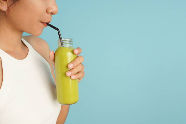 copy space of woman drinking smoothie avocado with straw on blue background