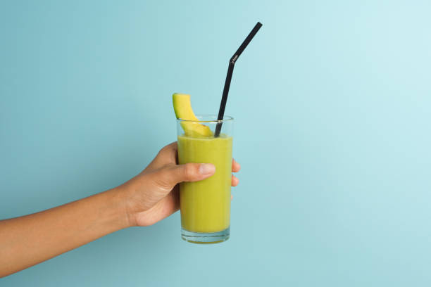 Close up hand holding juice avocado on blue background