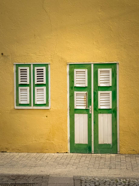istock Green shuttered door and window in a yellow wall 2198932517