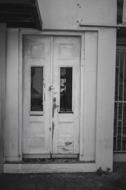 Old white wooden door in a white house in black and white