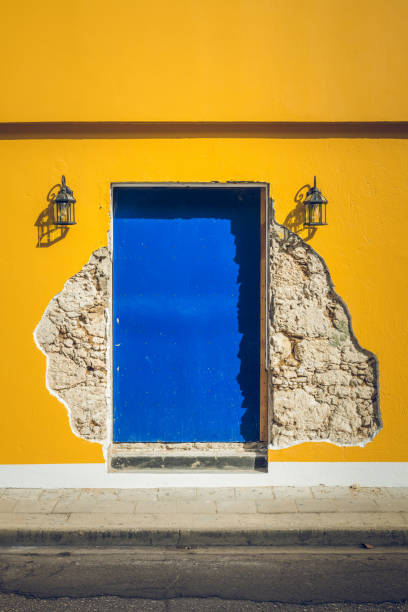 Bright blue Curacao door in a bright yellow peeling and broken wall