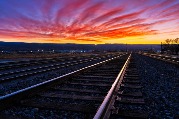 Urban Train Tracks with Colorful Sunset Sky - Diminishing perspective of railroad area with train tracks leading off into the distance. Colorful warm toned sky with copy space captured during blue hour. Grand Junction, Colorado USA.