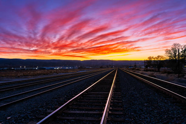 Urban Train Tracks with Colorful Sunset Sky - Diminishing perspective of railroad area with train tracks leading off into the distance. Colorful warm toned sky with copy space captured during blue hour. Grand Junction, Colorado USA.