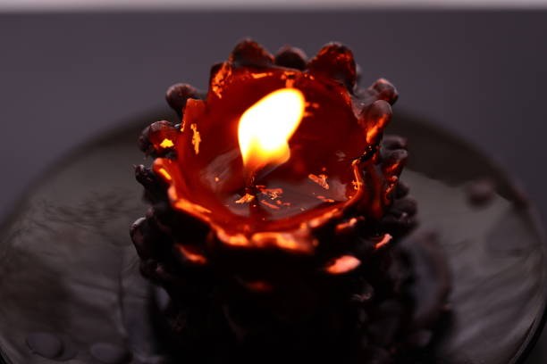 A lit candle sits on top of a black plate, ready for use or decoration.