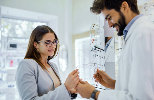 istock Customer tries on glasses while consulting with an eye care professional in a bright optical store 2198939168