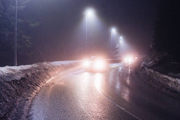 The car stands on the territory of the house at night. Light headlights through the fence