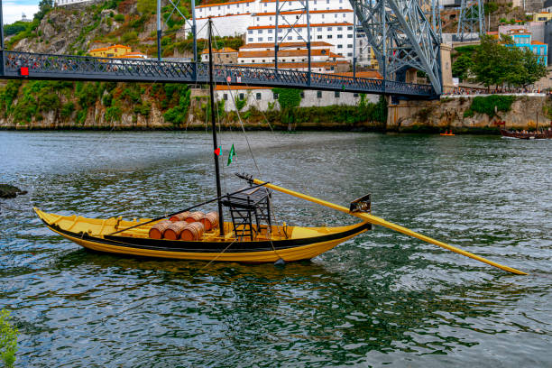 A yellow boat floating peacefully on the river under the bridge in Porto