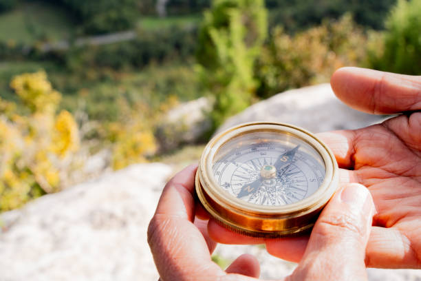istock Weathered hands clasping vintage compass, guiding path across misty wilderness terrain with purposeful navigation 2198944946