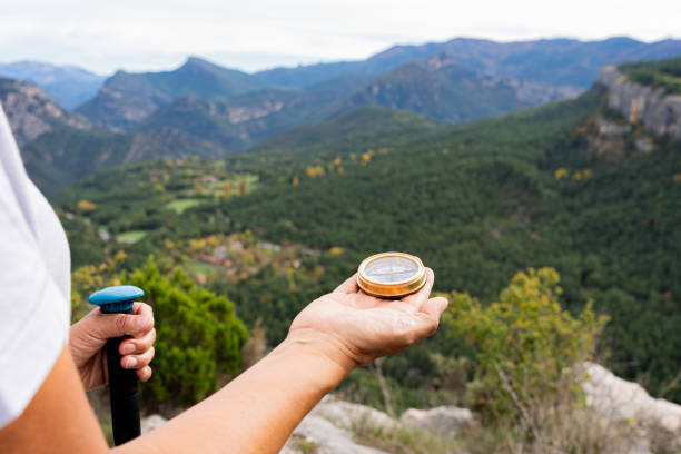 Female hiker navigating alpine terrain, gripping compass and trekking pole amid colorful fall landscape, mountain peaks framing rugged wilderness journey
