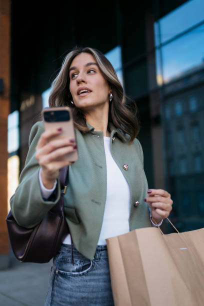 istock Young woman using smartphone while carrying shopping bag 2198947431