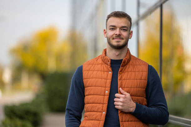 istock young man in orange vest stay in a front glass building 2198948033