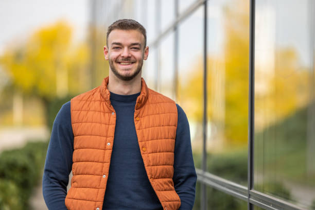 istock young man in orange vest stay in a front glass building 2198948041