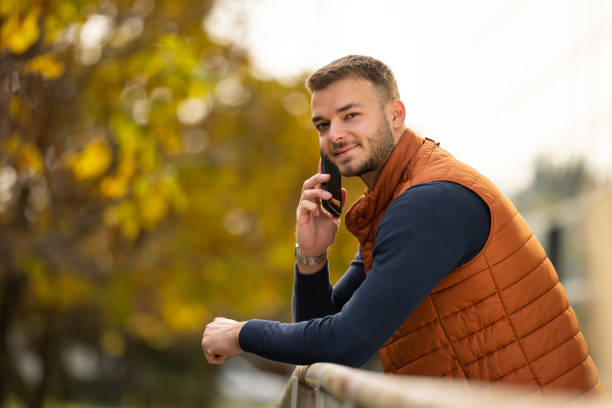istock young man in orange vest with mobile outdoor 2198948064