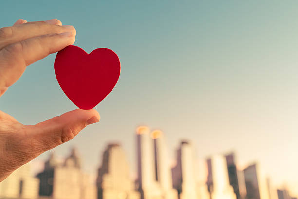 istock Hand holding red heart in the city. 2198949985