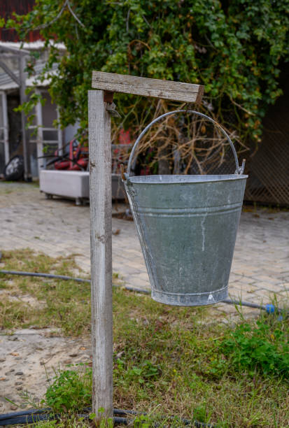 istock Old metal bucket hanging on a rustic wooden post in a countryside setting during cloudy weather 2198950192