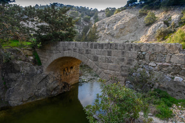 istock Ancient stone bridge nestled among lush greenery beside a tranquil river in a mountainous landscape 2198950835
