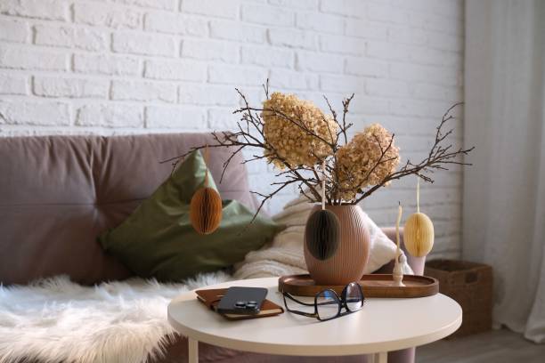 istock A beautifully cozy living room with modern easter home decor that includes vase with dry branches, flowers and eggs, notebook, mobile phone, glasses, candles on coffee table. 2198952119