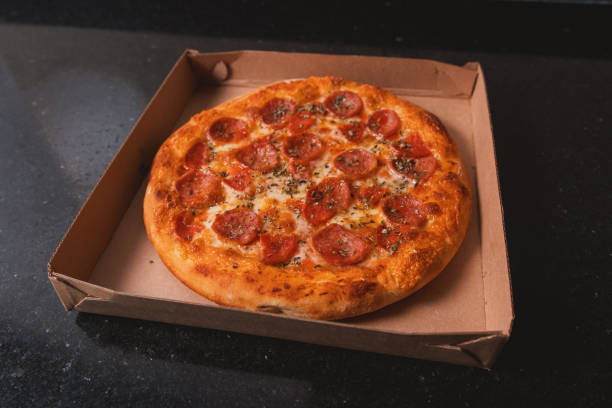 istock Pepperoni pizza placed on top of a cardboard box ready for delivery. 2198955006