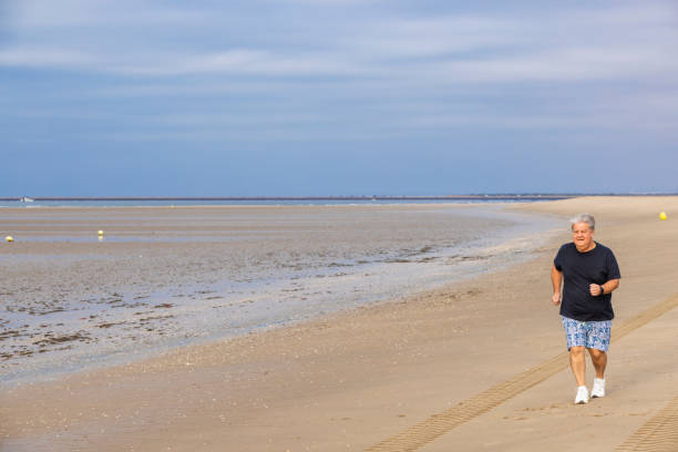 istock Senior Man Jogging Along Isla Canela Beach, Spain 2198956613