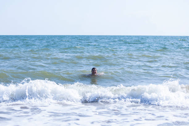 Dynamic and thrilling waves crash onto the shore at Isla Canela Beach as tourists enjoy the sea. A great stock photo for adventure travel, coastal fun, and water sports promotions