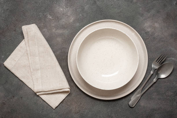 istock Two empty plates with cutlery and linen napkin on dark rustic background, top view, minimal table setting 2198961392