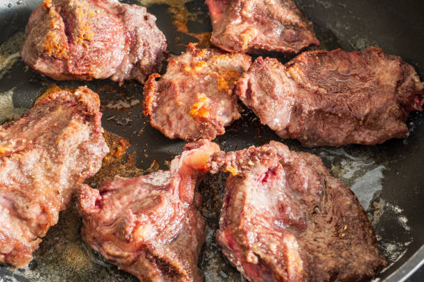 pieces of seasoned beef cheeks sprinkled with flour frying in oil several pieces of seasoned beef cheeks sprinkled with flour frying in oil braising pan stock pictures, royalty-free photos & images