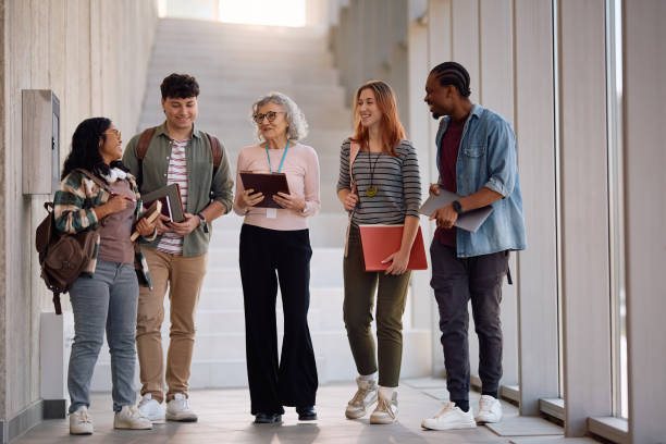 istock Happy university students talking to their teacher while walking through hallway. 2198962256