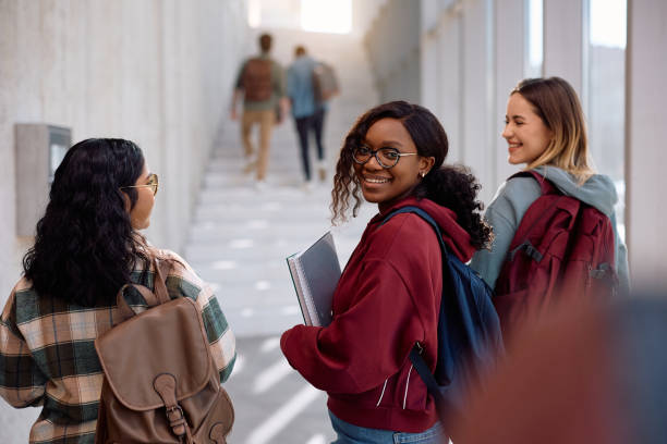 istock Happy black students going to a lecture with her classmates and looking at camera. 2198962288