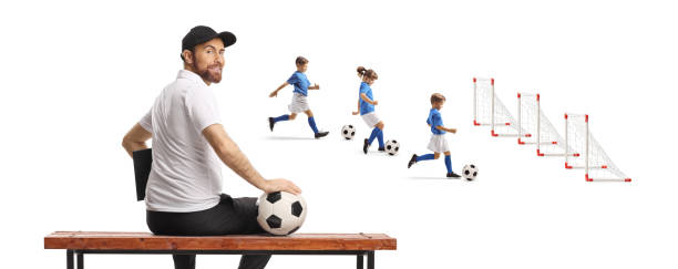 istock Football coach sitting on a bench and watching children training 2198962930