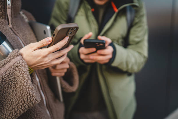 istock close up on male and female hands use mobile phone in front black wall 2198963126