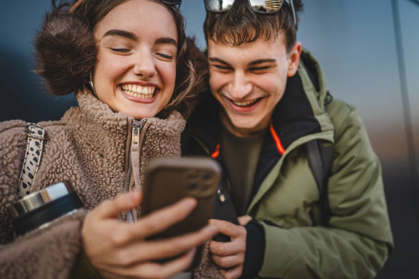 istock young couple stand and use cellphone in front black wall outdoor 2198963846