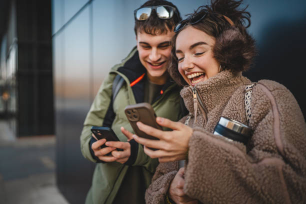 istock young couple stand and use cellphone in front black wall outdoor 2198963883