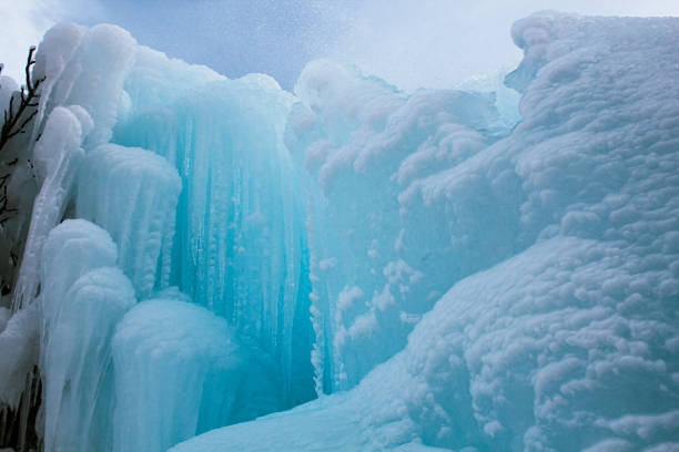 Detailed macro of a translucent blue ice plate with smooth refractions and snow accents near a rocky shoreline, highlighting clarity, layers, and natural shapes under soft overcast light with copy space for text. Ideal for nature, purity, climate, and texture themes, emphasizing clean Baikal ice, extreme cold, and minimalist abstract aesthetics in an outdoor scene.