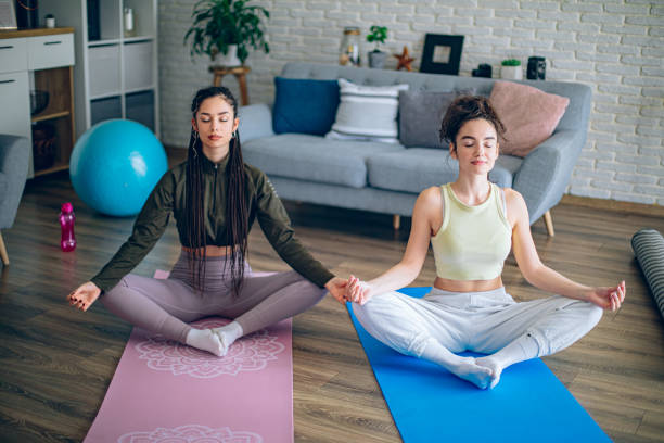 istock Two young women practicing yoga together at home 2198969921