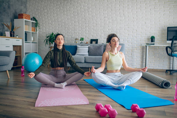 istock Two young women practicing yoga together at home 2198969957