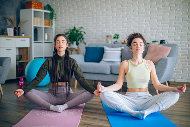 istock Two young women practicing yoga together at home 2198970054