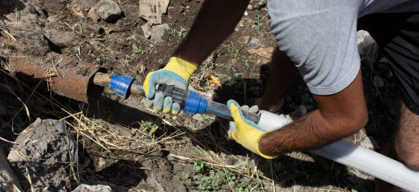 Plumber connects a water pipe in a trench