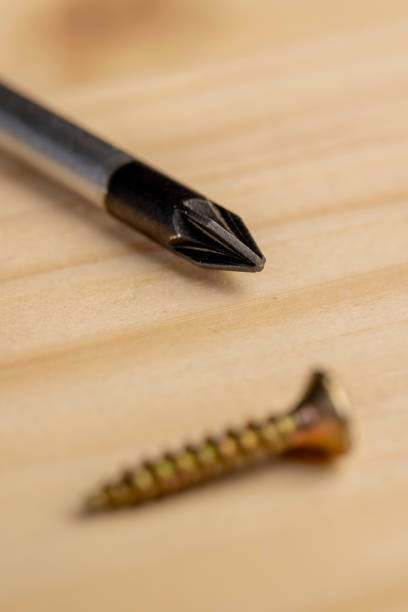 screwdriver and golden decorative self  tapping screws for fixing wood lying on a pine board, a group of tools for construction work
