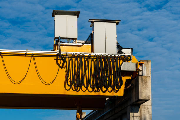Heavy yellow overhead crane with coiled cables and power boxes at a construction site. This setup highlights the essential equipment used for lifting materials high above ground.