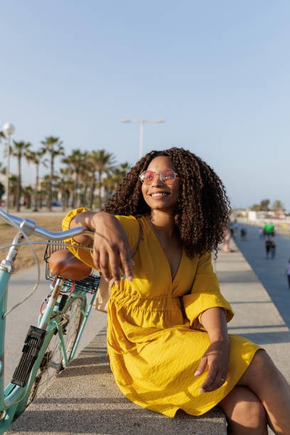 istock Young woman relaxing with her bicycle on a sunny day at beach 2198984523