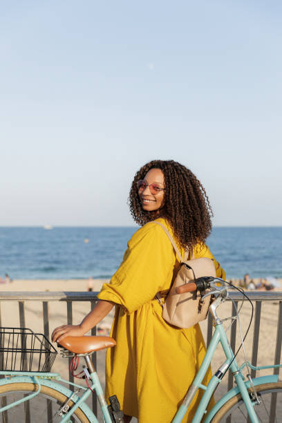 istock Young woman walking with bicycle on beach boardwalk 2198985054