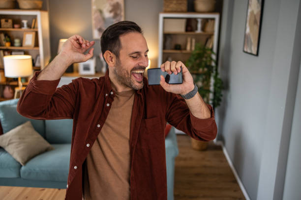 istock Young man dancing and singing into phone like a microphone 2198985544